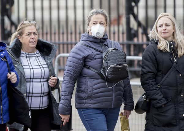 A woman wearing a protective face mask walks past Buckingham Palace, London, as Health Secretary Matt Hancock has said ministers are yet to make a decision on whether to ban gatherings of over 500 people in the rest of the UK, after Scotland said it would bring in restrictions from Monday.