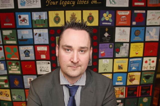 Kenny Donaldson, spokesman of Innocent Victims United, in front of a quilt made by people who lost a loved one to terrorism in the Troubles