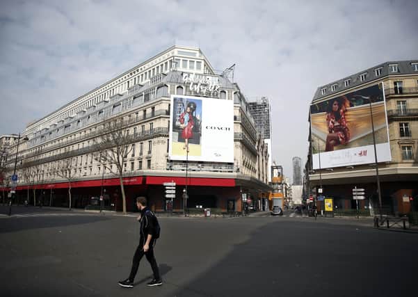 A man walks near Galeries Lafayette department store in a deserted Paris yesterday. Ben Lowry writes: "There were good reasons to delay lockdown, which could cause a global depression, plunging millions of people into poverty and early death. Also millions of people will soon be living on top of each other for months, leading to frustration and in some cases violence"  (AP Photo/Thibault Camus)