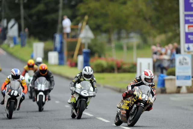 Sam Dunlop leads cousins William (6) and Paul Robinson (18) into Armoy village in the 125cc race.