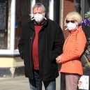 Members of the public wearing masks queue to enter shops as the UK continues in lockdown to help curb the spread of the coronavirus.