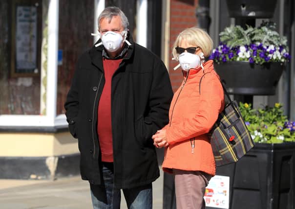 Members of the public wearing masks queue to enter shops as the UK continues in lockdown to help curb the spread of the coronavirus.