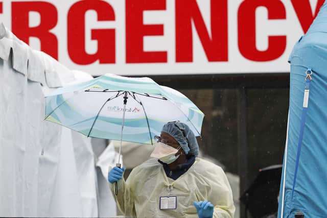 A medical worker holds an umbrella as she checks to to see if anyone is waiting in line outside a COVID-19 testing centre