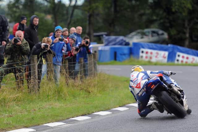 Fans look on as Guy Martin leads a wet Supersport race at the Ulster Grand Prix on the Tyco Suzuki in 2013.