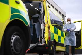 A paramedic wearing personal protective equipment (PPE) exits an ambulance