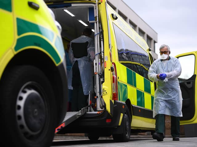 A paramedic wearing personal protective equipment (PPE) exits an ambulance