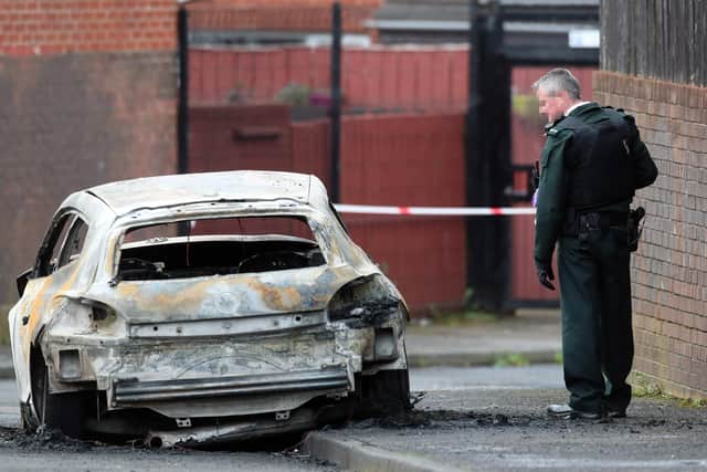 A PSNI officer beside a burnt out car following the shooting of a man in Etna Drive in the Ardoyne area of Belfast today. 
 PICTURE BY STEPHEN DAVISON