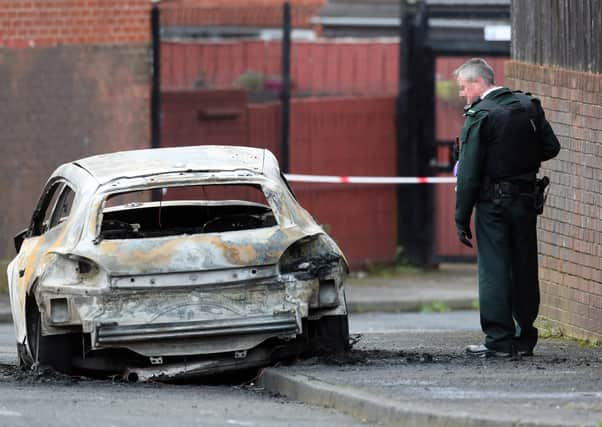 A PSNI officer beside a burnt out car following the shooting of a man in Etna Drive in the Ardoyne area of Belfast. 
 PICTURE BY STEPHEN DAVISON