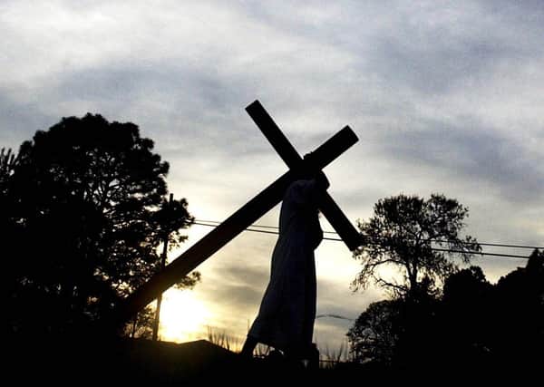 Christopher Riddle portrays Jesus Christ as he carries the cross down Highway 210 in Spring Lake, USA, on his way to Full Gospel Zion Church during Good Friday, April 14, 2006. (AP Photo/The Fayetteville Observer, Stephanie Bruce)