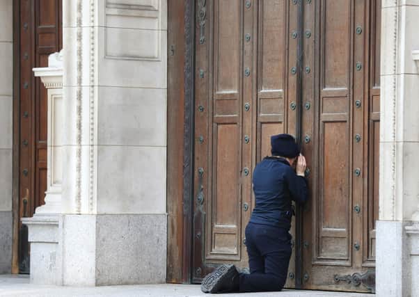 A woman prays at the closed doors of Westminster Cathedral ahead of the Easter morning mass, London