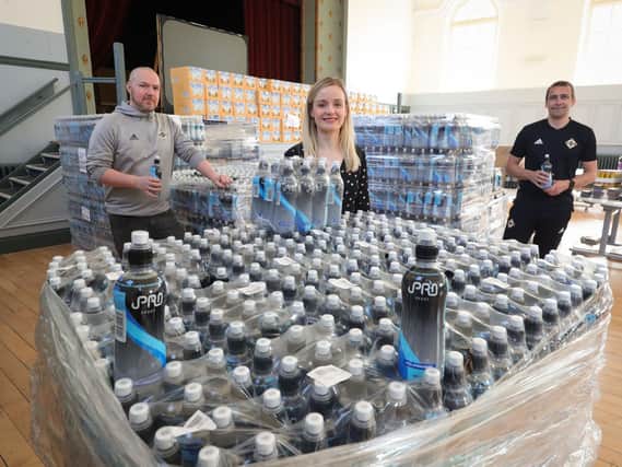 Kerri McAuley from the Belfast Trust Covid-19 Donations Team accepts the donation from the Irish FA and iPRO. Stephen Bogle (left) and David Currie from the Irish FA, with help from TR Logistics, delivered the 10,000 bottles of water.