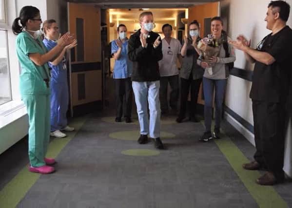 NHS Trust of radiographer Paul Skegg walking out of hospital, as NHS staff lined the corridors clapping and cheering for him after he beat coronavirus. PA Photo.