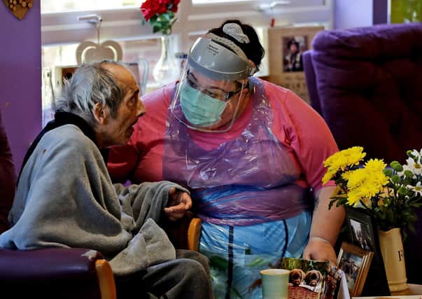 A nurse in full personal protective equipment speaks to a resident at a care home