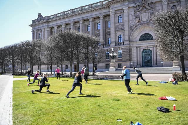 People exercise on a lawn, keeping distance outside the old parliament building in Stockholm, Sweden on Tuesday. But the country that has not implemented the measures termed ‘lockdown’ (Fredrik Sandberg/TT News Agency via AP)