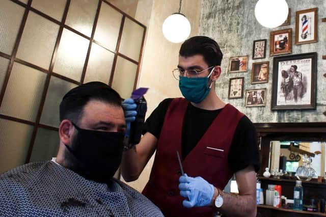 A Barber wearing a protective mask and gloves.  (Photo by Milos Bicanski/Getty Images)