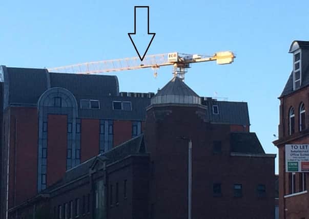 The arrow points to the 'agitated' man who was walking to and fro along the crane in Belfast city centre. The police cordon was so large the eye witness could not get any closer to take a better photo.