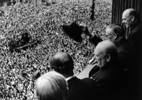 Prime Minister Winston Churchill waves to the crowds assembled in Whitehall, London on VE Day in 1945