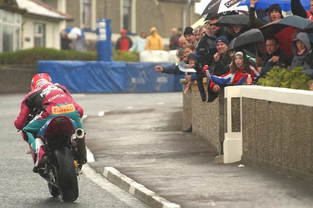 Cheered on by the fans, Ryan Farquhar powers up Millbank Avenue in the wet at the 2003 North West 200.