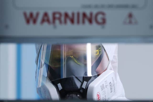 A Member of the PSNI Musgrave Street custody team looks through a cell door wearing the PPE required to interact with a suspected Covid-19 detained person in a detention block at the station in Belfast. PA Media was given exclusive first access to the Covid-19 block to witness how the Police Service of Northern Ireland (PSNI) has adapted to the challenges of custody in a pandemic.