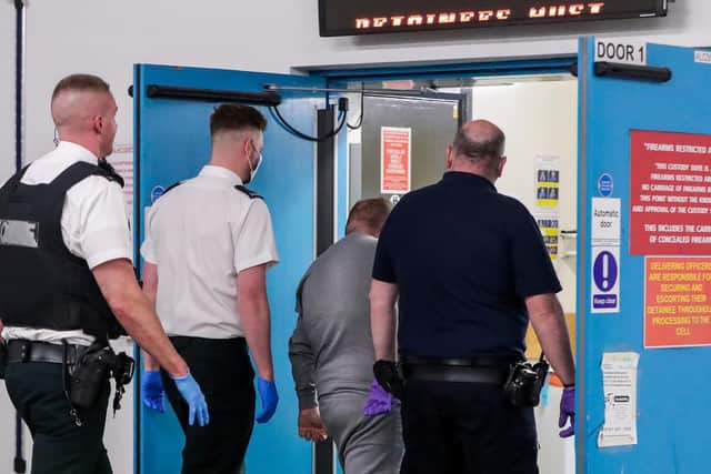 A man is detained by members of the PSNI and a custody officer at Musgrave Street custody suite in Belfast.