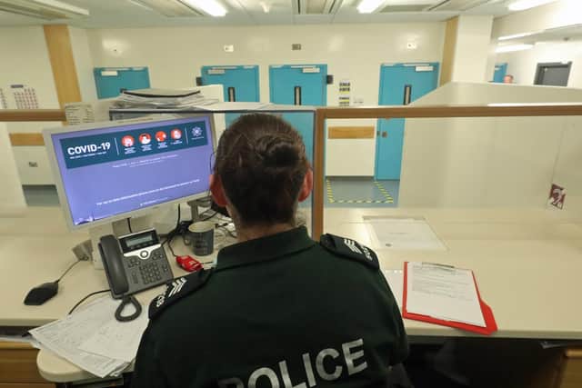 A Custody Seargent sits behind newly installed perspex screens at Musgrave Custody Suite in Belfast.