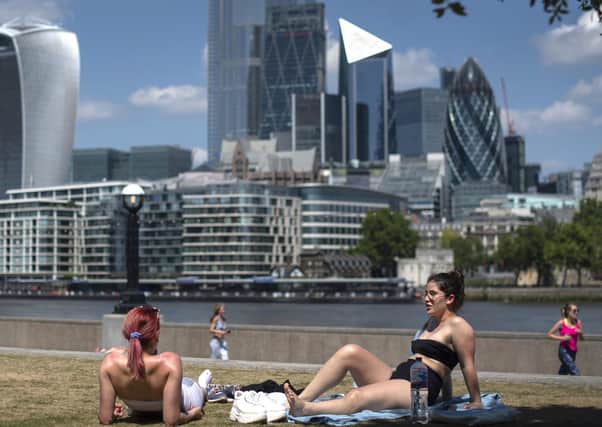 Two women enjoy the sun in Potters Field, London, as people flock to parks and beaches with lockdown measures eased on Thursday
