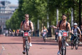 Cyclists ride along the Mall, as people enjoy the good weather in London