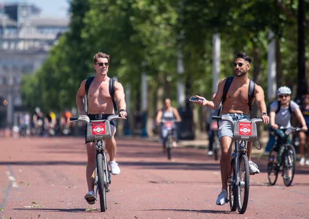 Cyclists ride along the Mall, as people enjoy the good weather in London