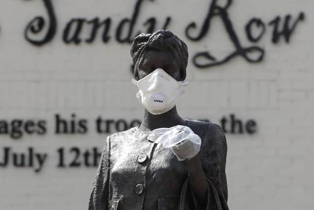 A statue by artist Ross Wilson entitled Mother Daughter Sister, celebrating female identity and culture, in Sandy Row Belfast is adorned with a mask and disposable gloves. (Photo: PA Wire)