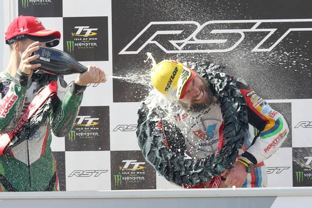 Runner-up Ian Hutchinson soaks Superbike TT winner Bruce Anstey with champagne on the rostrum in 2015.