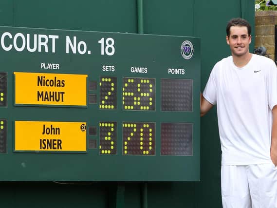 USA's John Isner stands by the final score board as he celebrates victory over France's Nicolas Mahut in their record breaking match on Court 18 during Day Four of the 2010 Wimbledon Championships