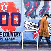 A man walks past a centenary mural on the Peppercorn Cafe, east Belfast
