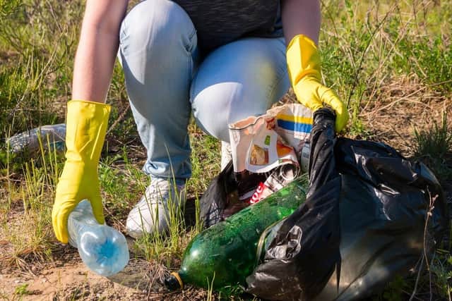 Volunteer girl in yellow gloves collects garbage