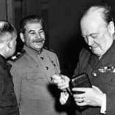 Winston Churchill  (1874 - 1965), the British prime minister, takes a new cigar as Joseph Stalin (1879 - 1953) the Soviet leader smiles with approval at the Crimea conference, Yalta.   (Photo by Keystone/Getty Images)