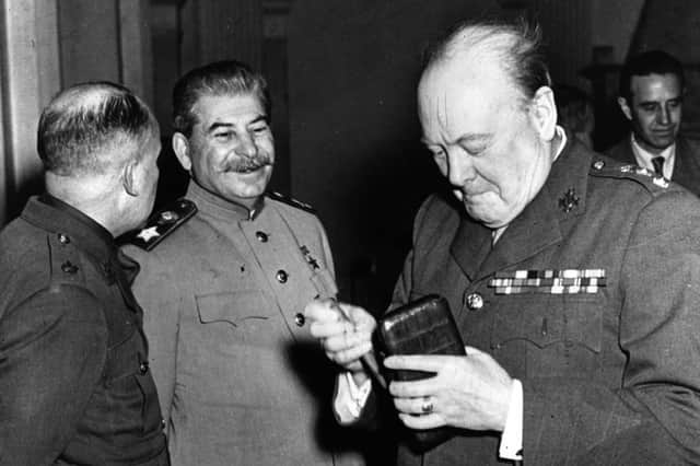 Winston Churchill  (1874 - 1965), the British prime minister, takes a new cigar as Joseph Stalin (1879 - 1953) the Soviet leader smiles with approval at the Crimea conference, Yalta.   (Photo by Keystone/Getty Images)