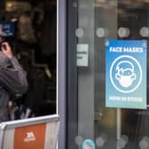 A man puts on his face covering as he walks into Trespass retail store in Belfast. Picture date: Monday November 22 2021.