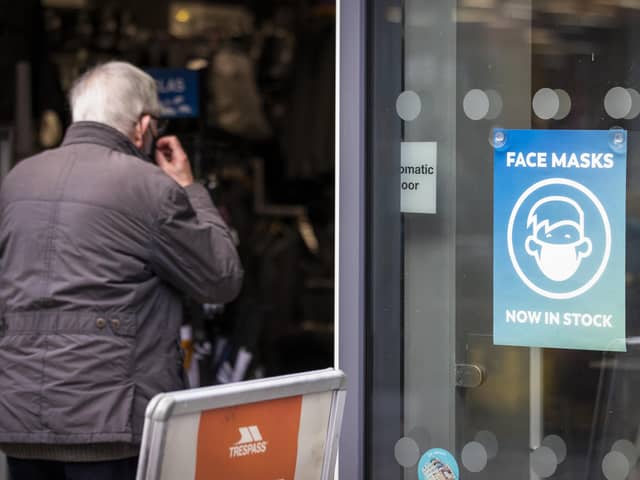 A man puts on his face covering as he walks into Trespass retail store in Belfast. Picture date: Monday November 22 2021.