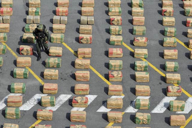 A police officer walks among seized packages of drugs in Cali, Colombia. The people of Colombia have suffered much violence over drugs trafficking and in the decades-long conflict with the outlawed Revolutionary Armed Forces of Colombia (FARC)