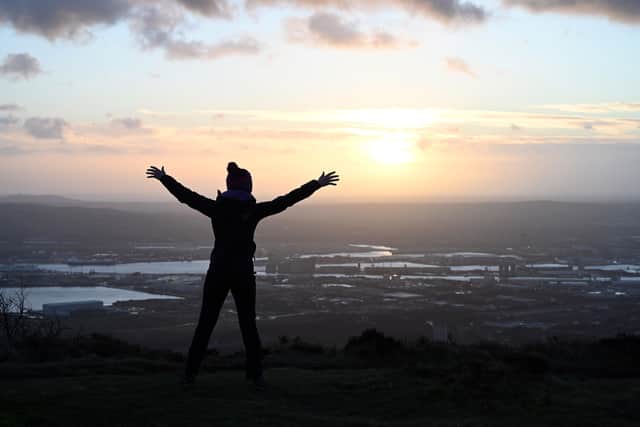 One of the people on the top of Cave Hill watch as the sun rises over Belfast on NewvYear's morning 2022. Picture: Michael Cooper