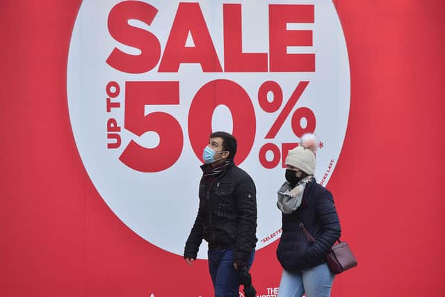 People in Belfast city centre walk past a sign advertising January sales