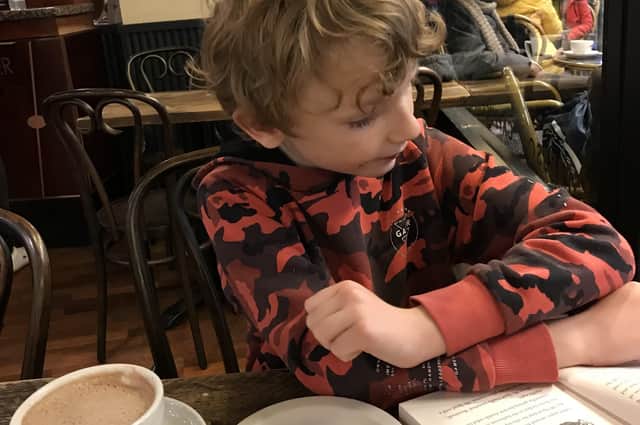 My son engrossed in his new book as his dad spills coffee on his jumper