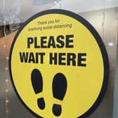 Sign in a bistro window in Belfast asking customers to practice social distancing and to wait to be seated.