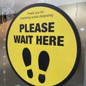 Signage in a bistro window in Belfast asking customers to practice social distancing and to wait to be seated.
