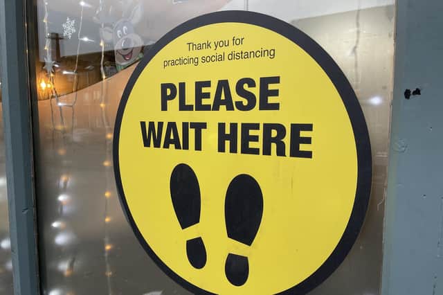 Signage in a bistro window in Belfast asking customers to practice social distancing and to wait to be seated.