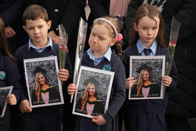 Pupils from Ashling Murphy's class hold photographs of her and red roses outside St Brigid's Church, Mountbolus, Co Offaly, ahead of the funeral of the schoolteacher who was murdered in Tullamore, Co Offaly last Wednesday. PA image