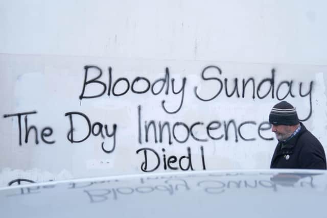 A man walks past graffiti on a wall in the Creggan area of Derry ahead of a remembrance walk to mark the 50th anniversary of Bloody Sunday