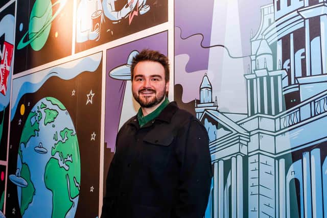 Ethan Smyth poses in front of his alien invasion inspired mural