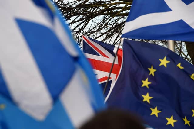 Pro-Union activists wave a Union flag (C) as Scottish Saltire and EU flags fly during an anti-Conservative government, pro-Scottish independence, and anti-Brexit demonstration outside Holyrood, the seat of the Scottish Parliament in Edinburgh