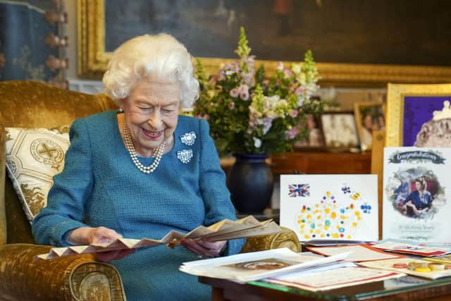 Queen Elizabeth II looks at a fan as she views a display of memorabilia from her Golden and Platinum Jubilees in the Oak Room at Windsor Castle