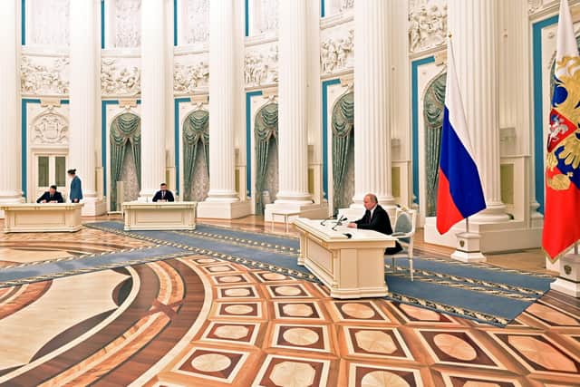 Russian President Vladimir Putin, right, signs a document recognising the independence of separatist regions in eastern Ukraine with Denis Pushilin, the leader of the Donetsk People's Republic controlled by Russia-backed separatistsm centre, and Leonid Pasechnik, acting leader of self-proclaimed Luhansk People's Republics, left, in the Kremlin on Monday (Alexei Nikolsky, Sputnik, Kremlin Pool Photo via AP)